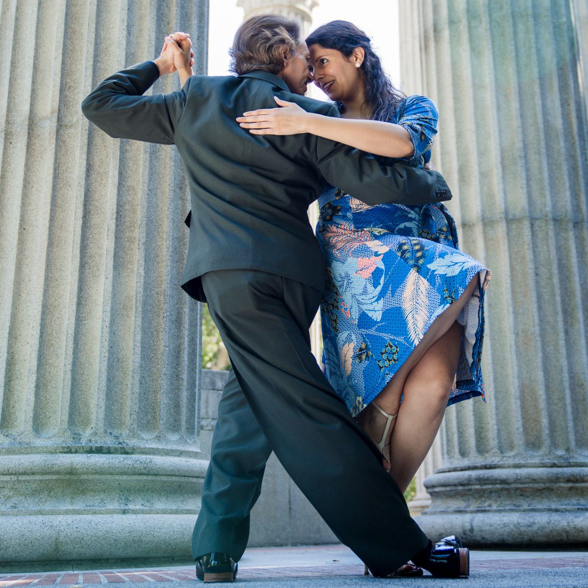 Argentine Tango dancing by Marcelo Solis and Mimi at Pulgas Water Temple in San Francisco. Marcelo wears a green olive suit and Mimi a blue dress with patterns